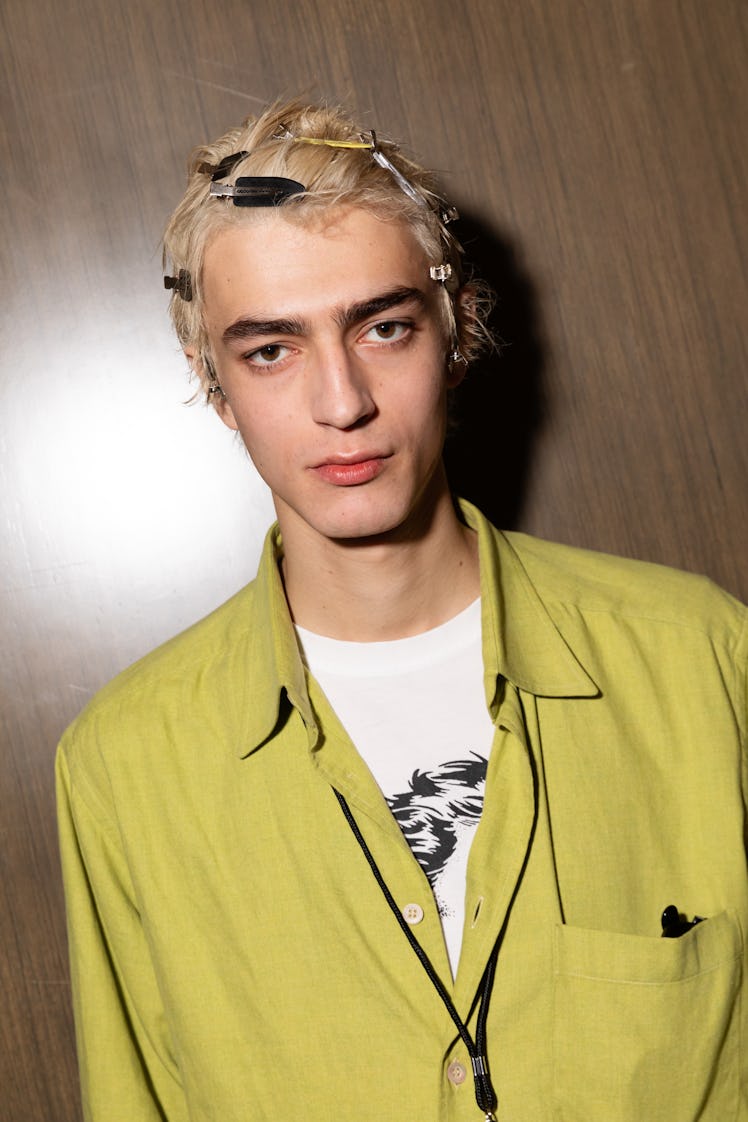 Male model with blonde hair full of clips posing for a photo