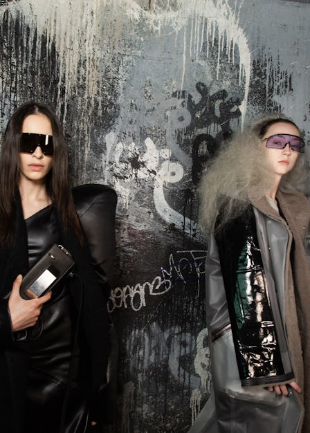 Two models wearing jackets by Rick Owens and posing in font of a graffiti painted wall