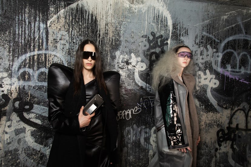 Two models wearing jackets by Rick Owens and posing in font of a graffiti painted wall