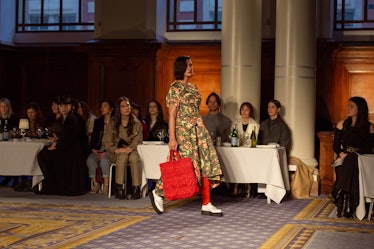 A model wearing a green-orange floral dress and a red bag at Molly Goddard’s London Fashion Week Sho...
