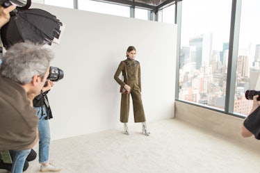 A female model getting photographed by photographers while wearing a green jumpsuit