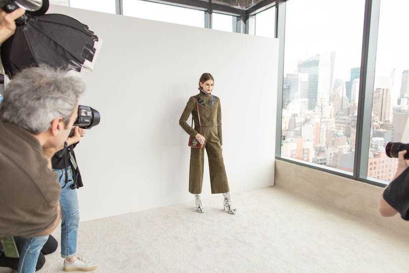 Kaia Gerber in a khaki suit and a bag by Longchamp and photographers around her
