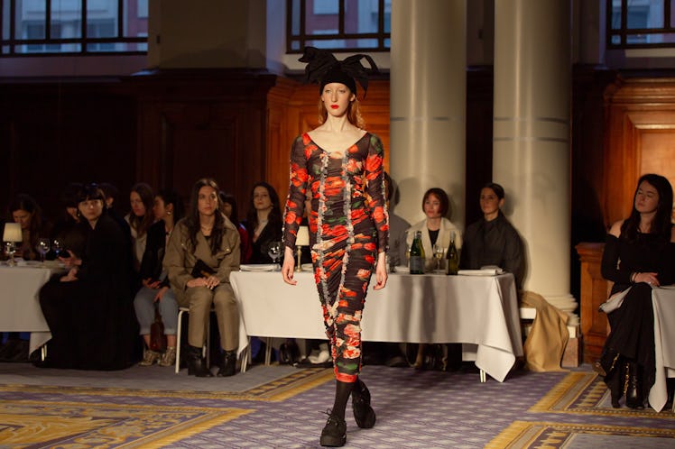A model wearing a red-black floral dress and a black hat at Molly Goddard’s London Fashion Week Show