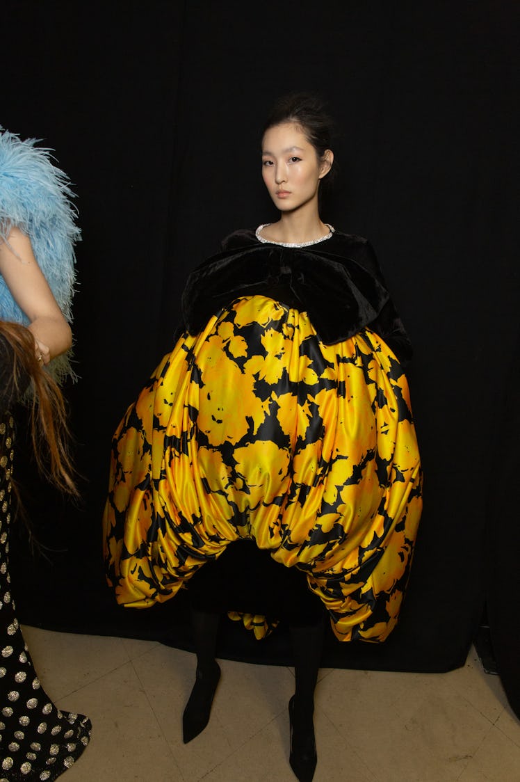 A model wearing a black-yellow floral puff dress backstage at Richard Quinn‘s fall collection