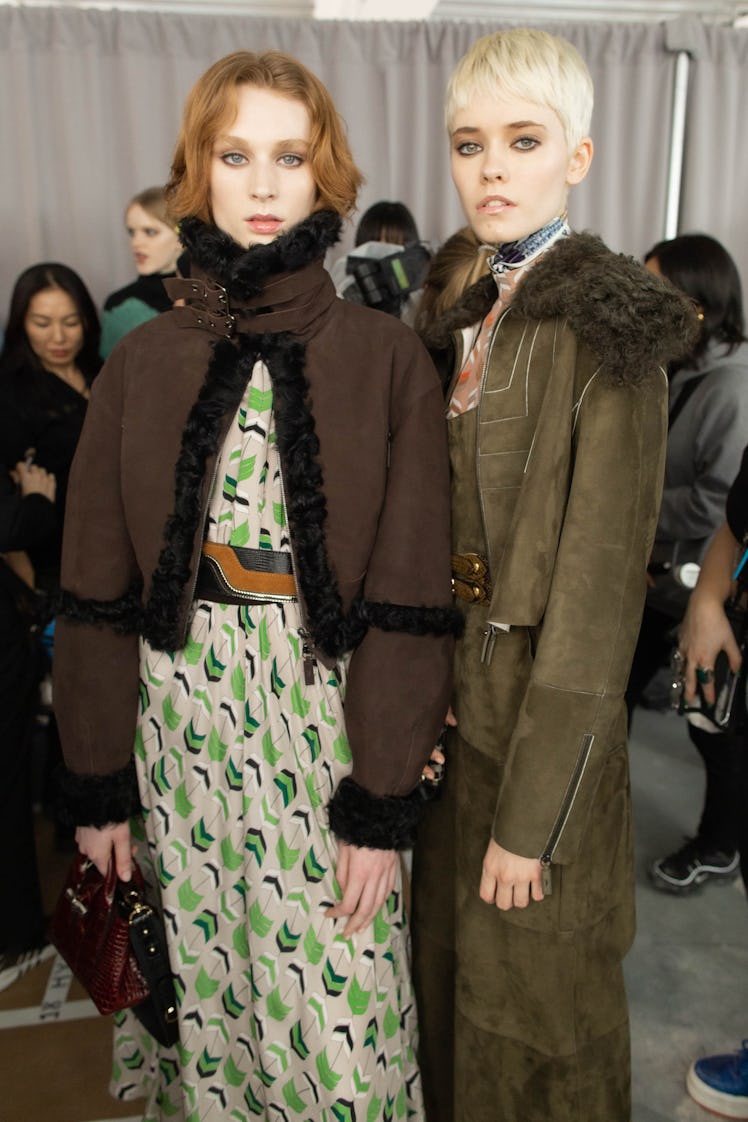 Two female models posing for a photo while wearing jackets and jumpsuits