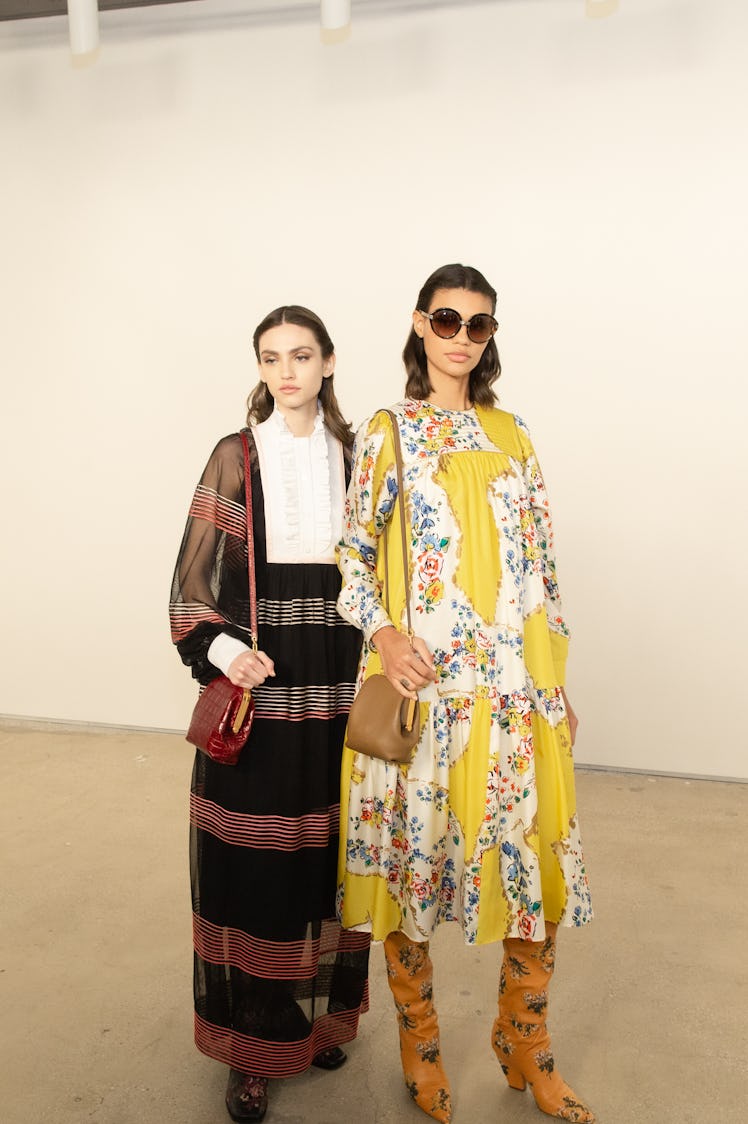 Two ladies in black and yellow dresses posing for a photo at the Tory Burch FW20 during New York Fas...