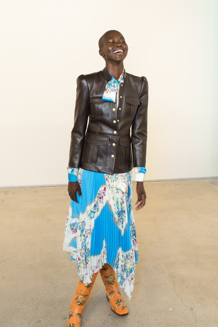 A bald female model posing in a black leather jacket and blue dress at the Tory Burch FW20 during Ne...