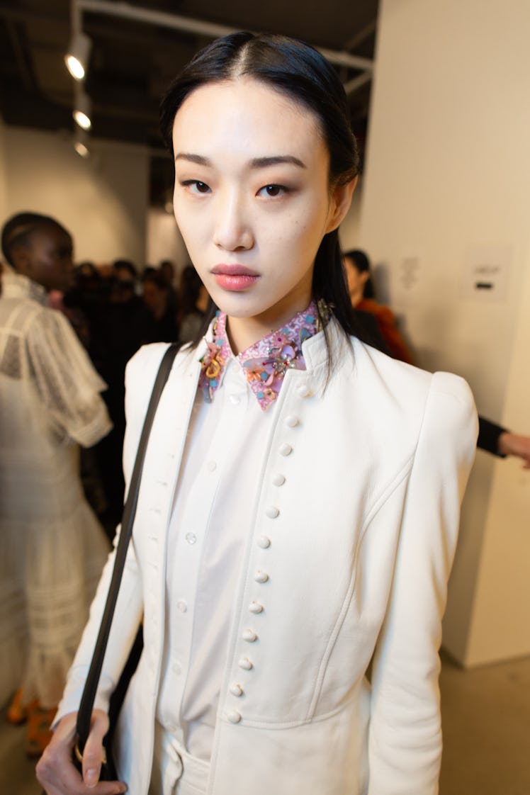 A female model wearing a white shirt and blazer combination
