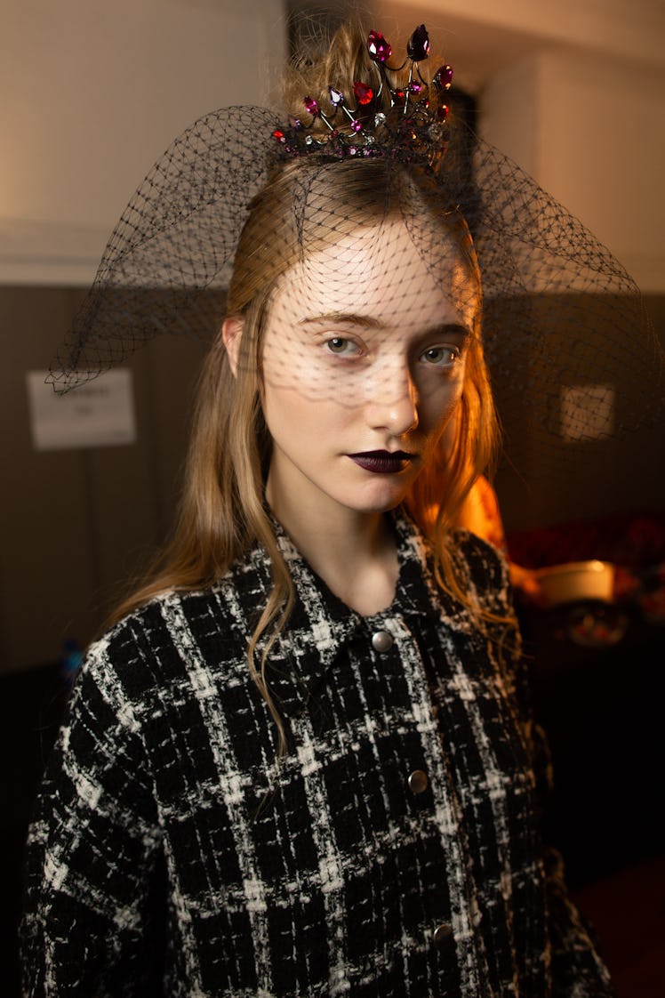 A female model posing while wearing a black plaid shirt and a black crown veil on her head