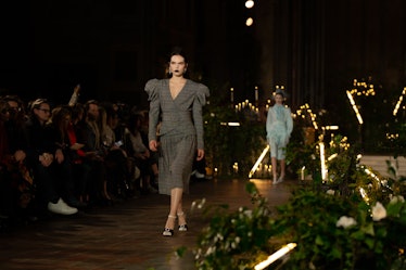 A female model walking while wearing a grey dress 