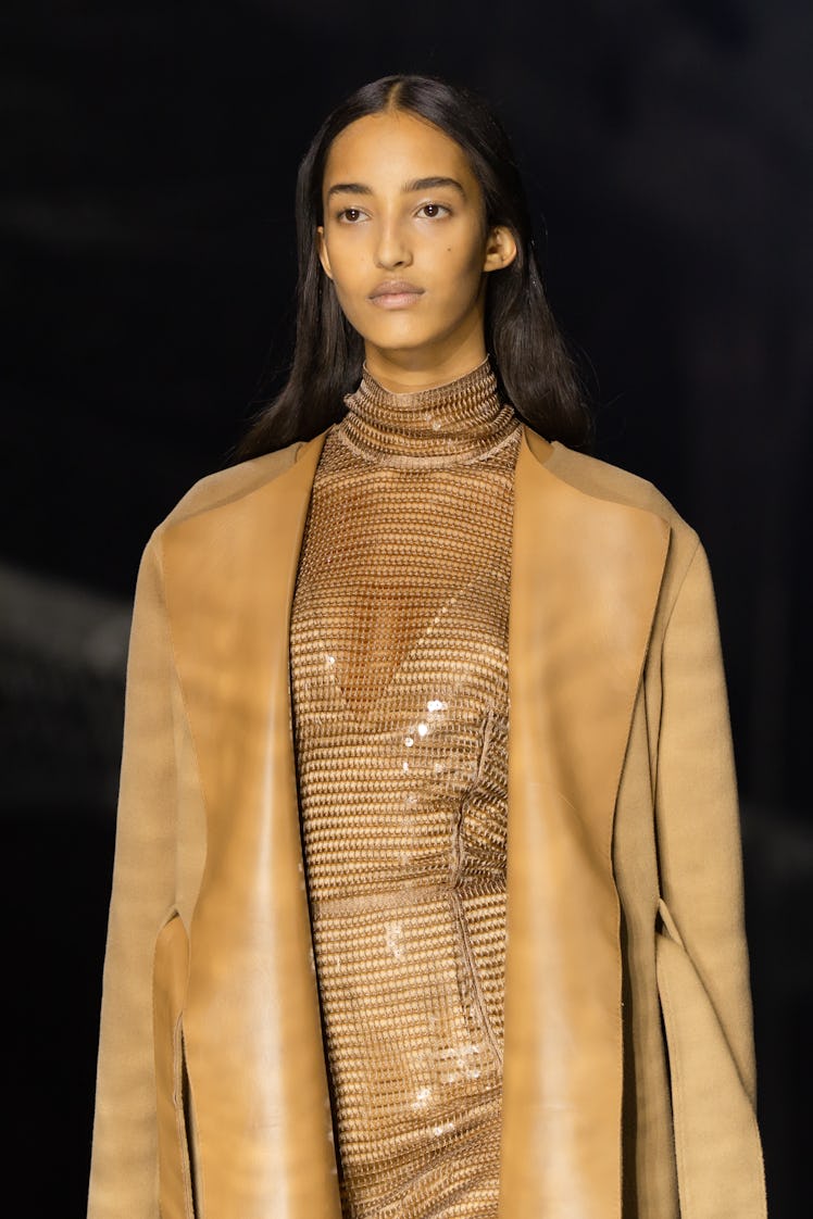 A model wearing a beige sequin dress and a beige coat at the Burberry Fall 2020 show