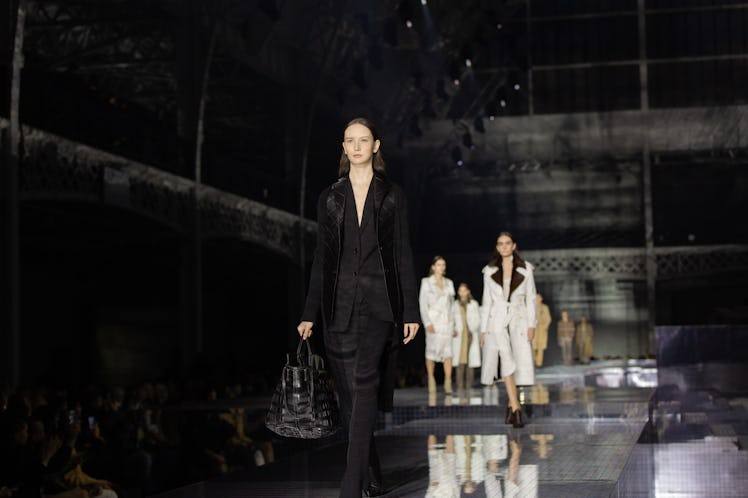 A model wearing a black suit, a black coat and a black bag at the Burberry Fall 2020 show