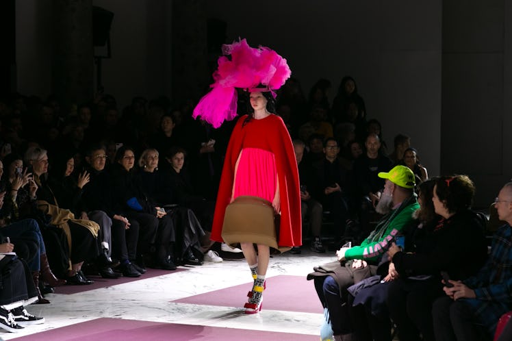 A model walking the runway at the Comme Des Garcons fall 2020 show in a red and brown dress and a pi...
