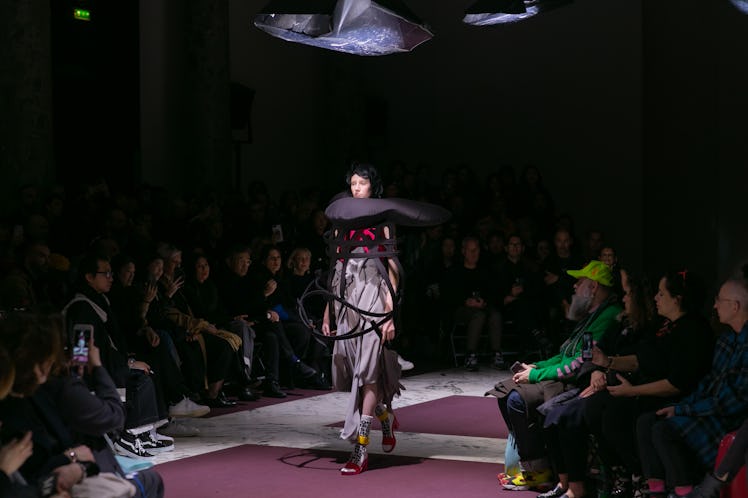 A model on Comme Des Garcons' fall 2020 runway in Paris in a grey dress and black wire construction ...