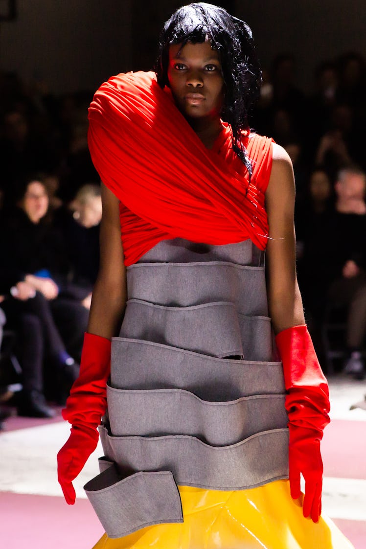 A model walking Comme Des Garcons' fall 2020 runway in Paris in a grey dress layered dress, with a y...
