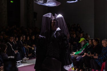A model on the Comme Des Garcons fall 2020 runway in Paris in a large black gown with a large black ...