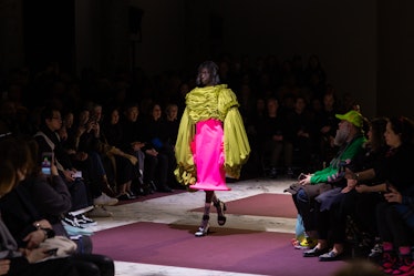 A model on the Comme Des Garcons fall 2020 runway in a yellow silk top with sleeved reaching her kne...