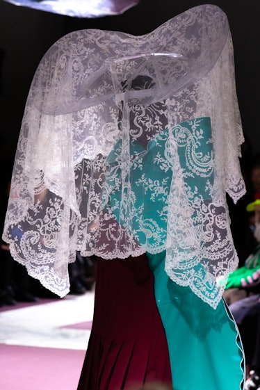 A model on the Comme Des Garcons fall 2020 runway in a turquoise and maroon dress and an embellished...