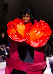 A model wearing a black-red dress with large orange segments by  Comme des Garçons