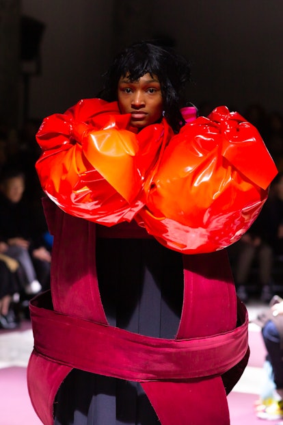 A model wearing a black-red dress with large orange segments by  Comme des Garçons