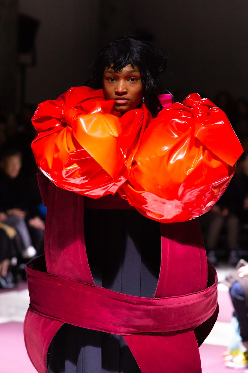 A model wearing a black-red dress with large orange segments by Comme des Garçons