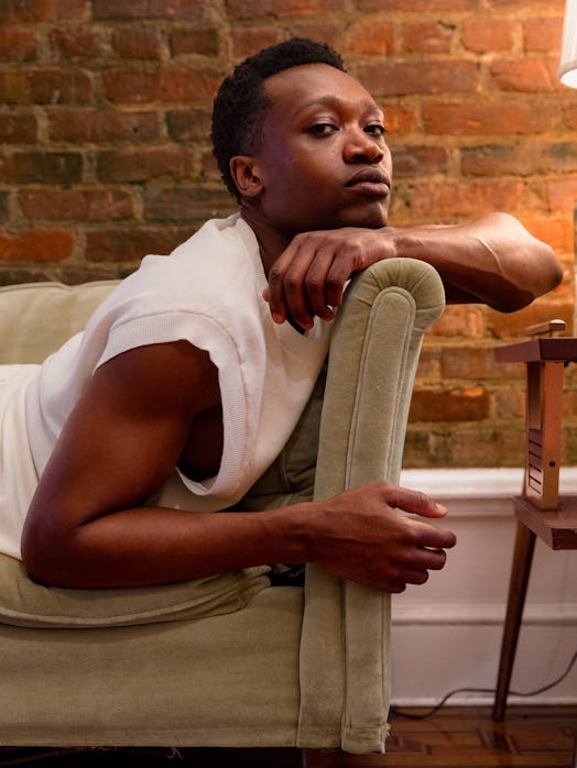 Ato Blankson-Wood lying on a couch while wearing a white shirt