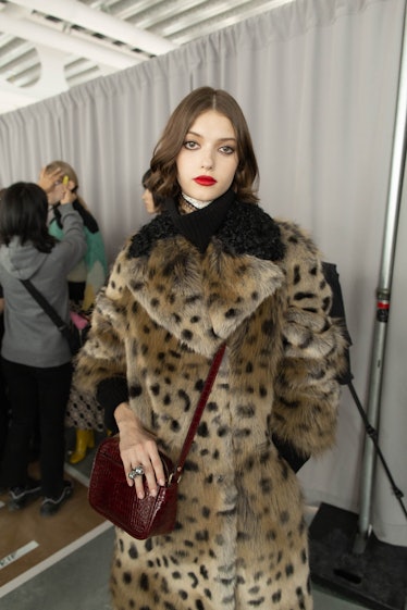 A female model posing while wearing a fur coat with leopard print 