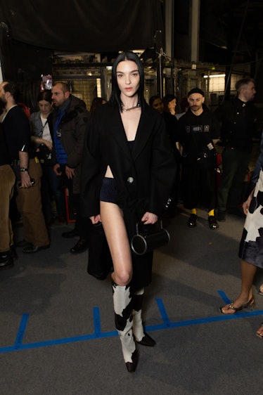 A model in a black coat, short and bandeau top and black-white boots backstage at Off-White