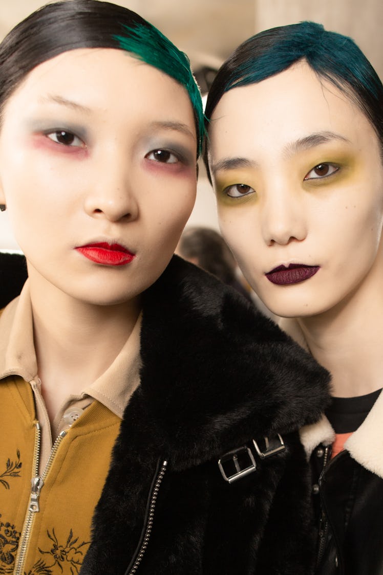 Two models with white makeup over their faces posing for a photo