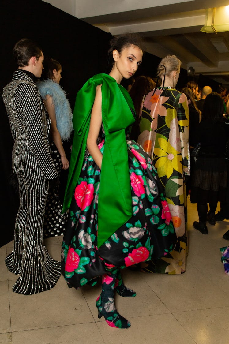 A model in a black-green-red floral dress with an oversized green ribbon at Richard Quinn‘s fall col...