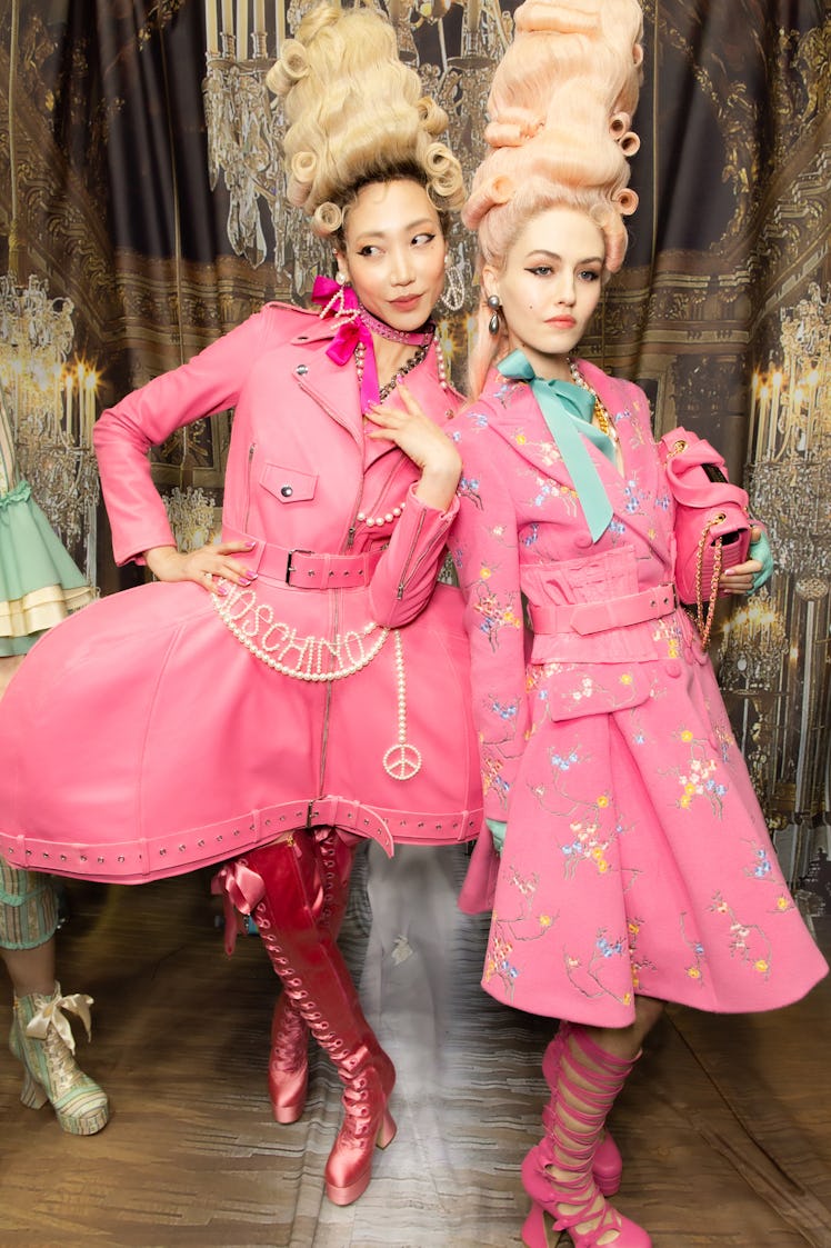 A model in a pink dress and boots and a model in a pink floral jacket and skirt and pink sandals