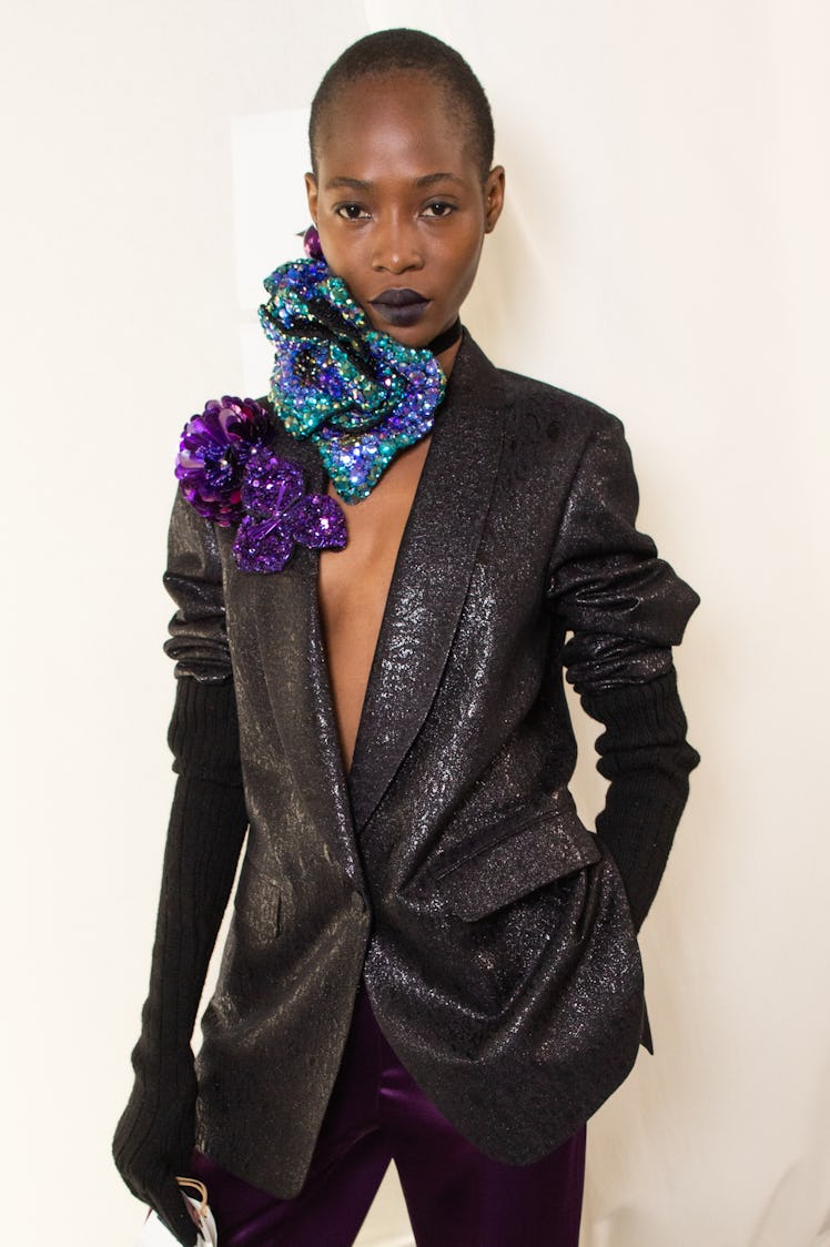 A model posing while wearing a black sequined blazer and gloves