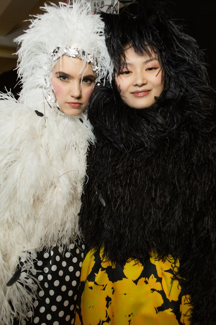 A model in a white feather dress and hat and a model in a black feather dress and hat at Richard Qui...