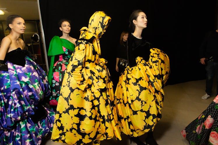 Two model in yellow-black floral dresses and a model in a blue floral dress at Richard Quinn‘s fall ...