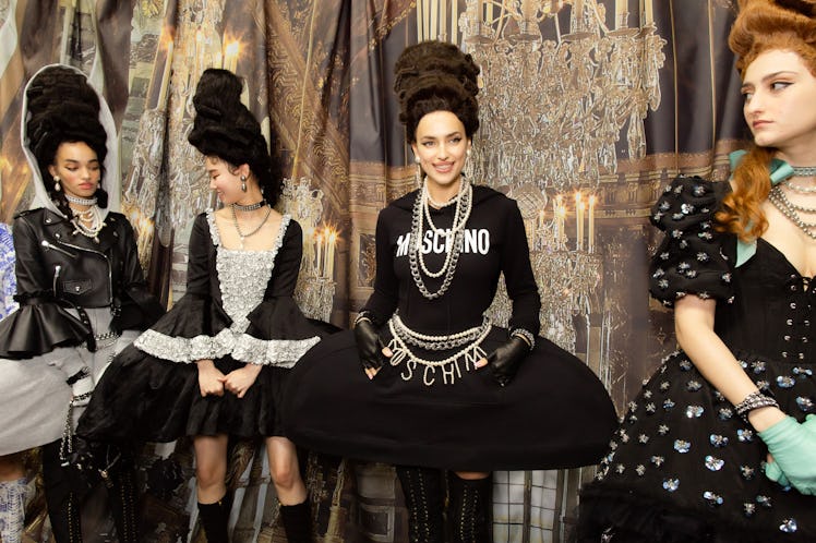Four models in black and white outfits standing and posing backstage at the Moschino Fall 2020 show