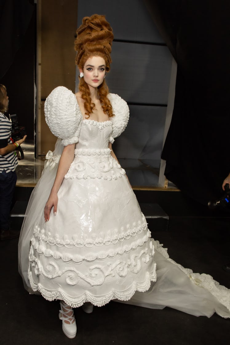 A model in a white lace and sequin dress backstage at the Moschino Fall 2020 show