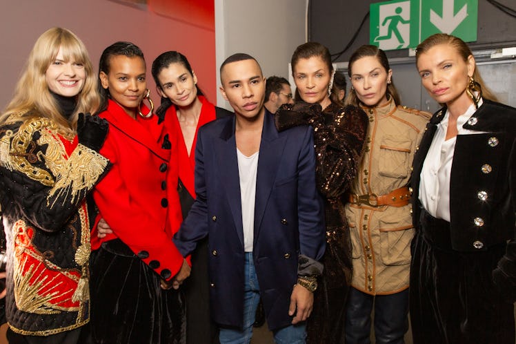 Olivier Rousteing posing with six models who are wearing Balmain Fall 2020 outfits