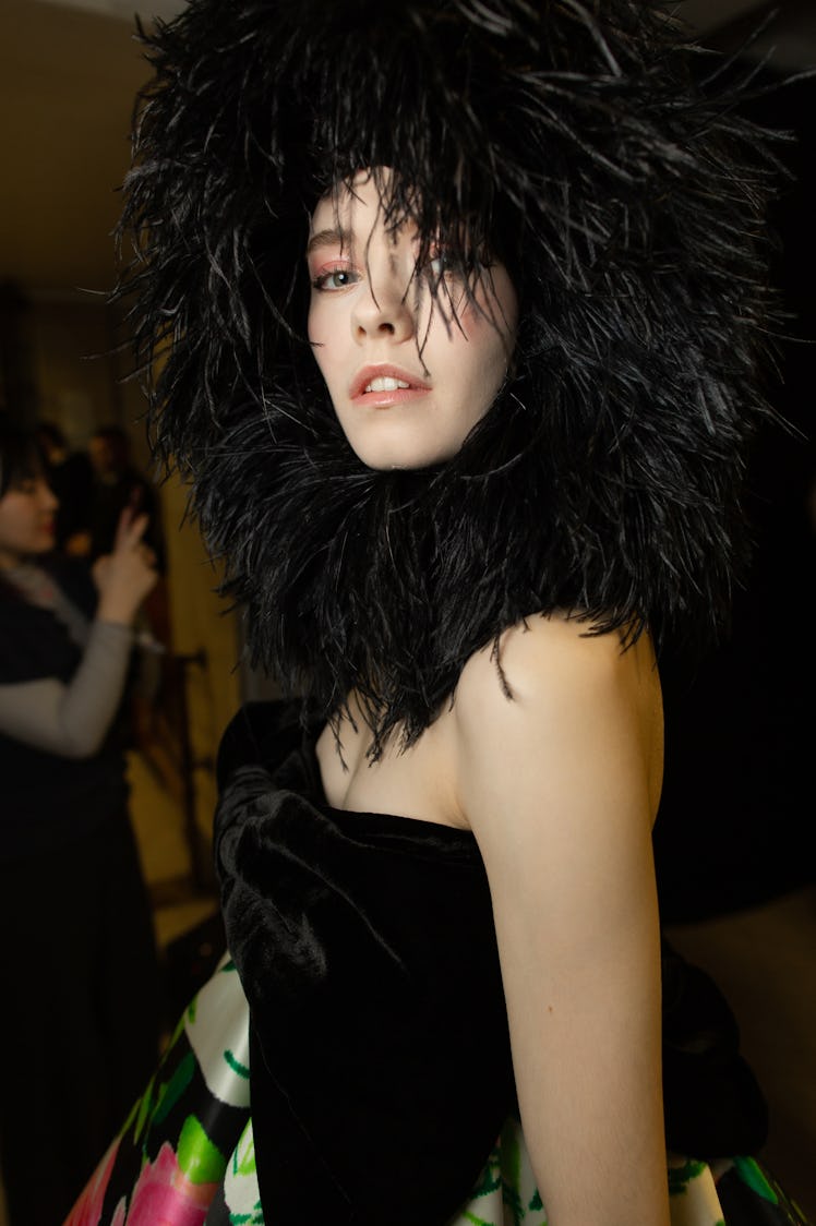 A model wearing a black dress and a black feather hat at Richard Quinn‘s fall collection