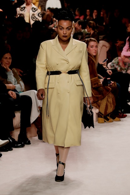 A plus-size model walking the runway in a Fendi show while wearing a beige blazer dress