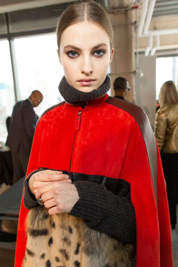 A brunette female model posing for a photo while wearing a red and black jacket