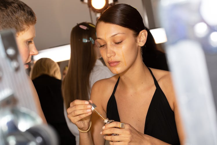 Bella Hadid putting drops under her eyes with a dropper before getting her makeup done