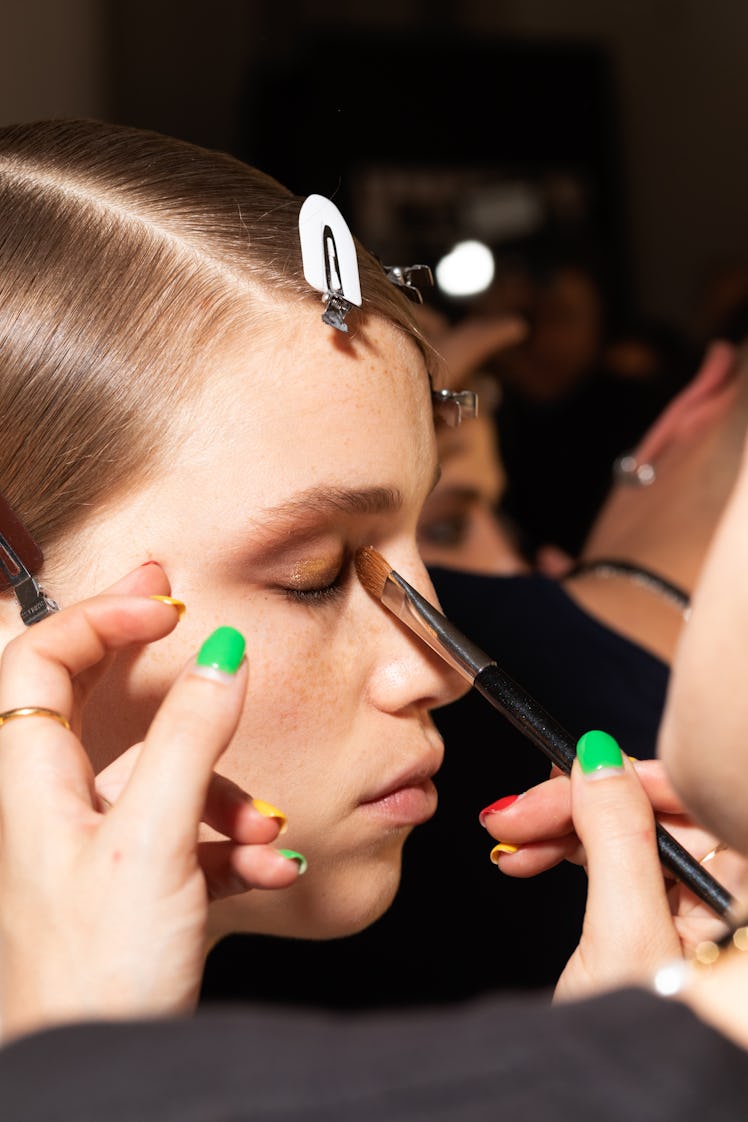 Model getting her eye makeup done by a makeup artist