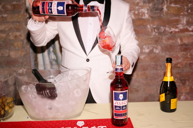 A bartender in a white tuxedo pouring liquor into a glass at the Save Venice party