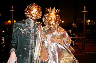 Two people with golden lion masks and traditional Venetian clothing at the Save Venice party