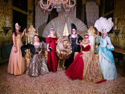 Women wearing Venetian masquerade masks and traditional gowns inside the Save Venice party