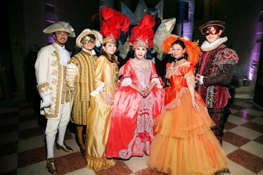 People standing in Venetian masquerade masks and traditional clothing inside the Save Venice party