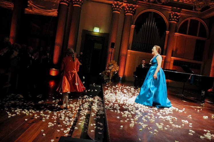 A woman in a blue dress surrounded by flower petals at the Save Venice party
