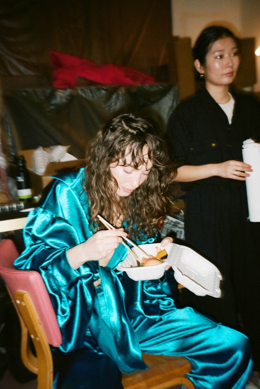 A model in her runway look eating takeout from Mission Chinese before the show