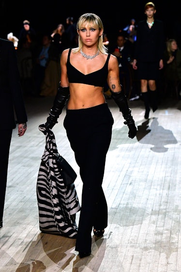 Miley Cyrus wearing a black bralette and black pants at a Marc Jacobs show