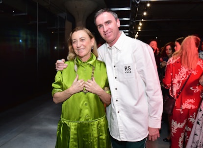 Fashion designer Raf Simons hugging Miuccia Prada while they pose for a picture